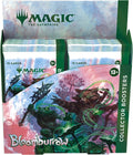 Colorful booster display box of fantasy trading cards featuring floral and creature artwork on a wooden tabletop